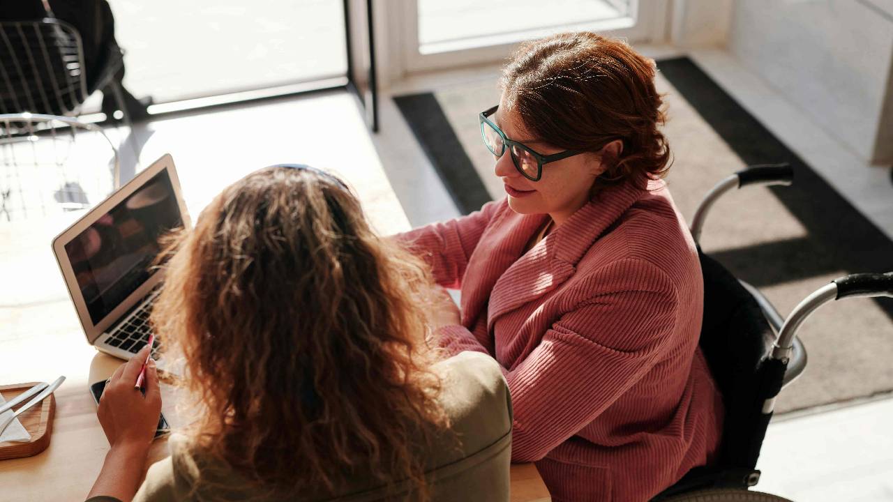 A woman on a wheelchair talking to her therapist
